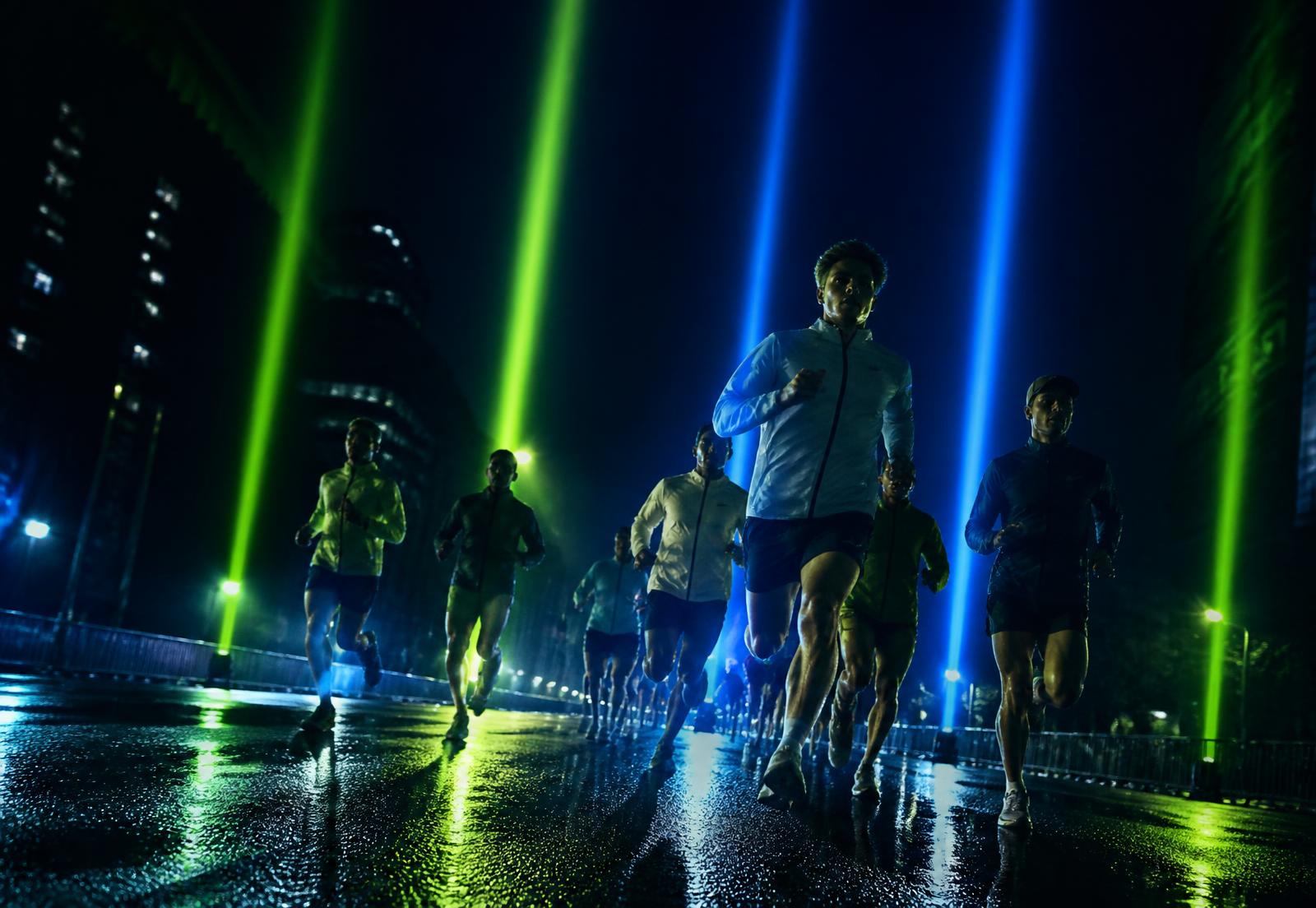 Corredores durante una carrera nocturna iluminada por haces de luz verde y azul